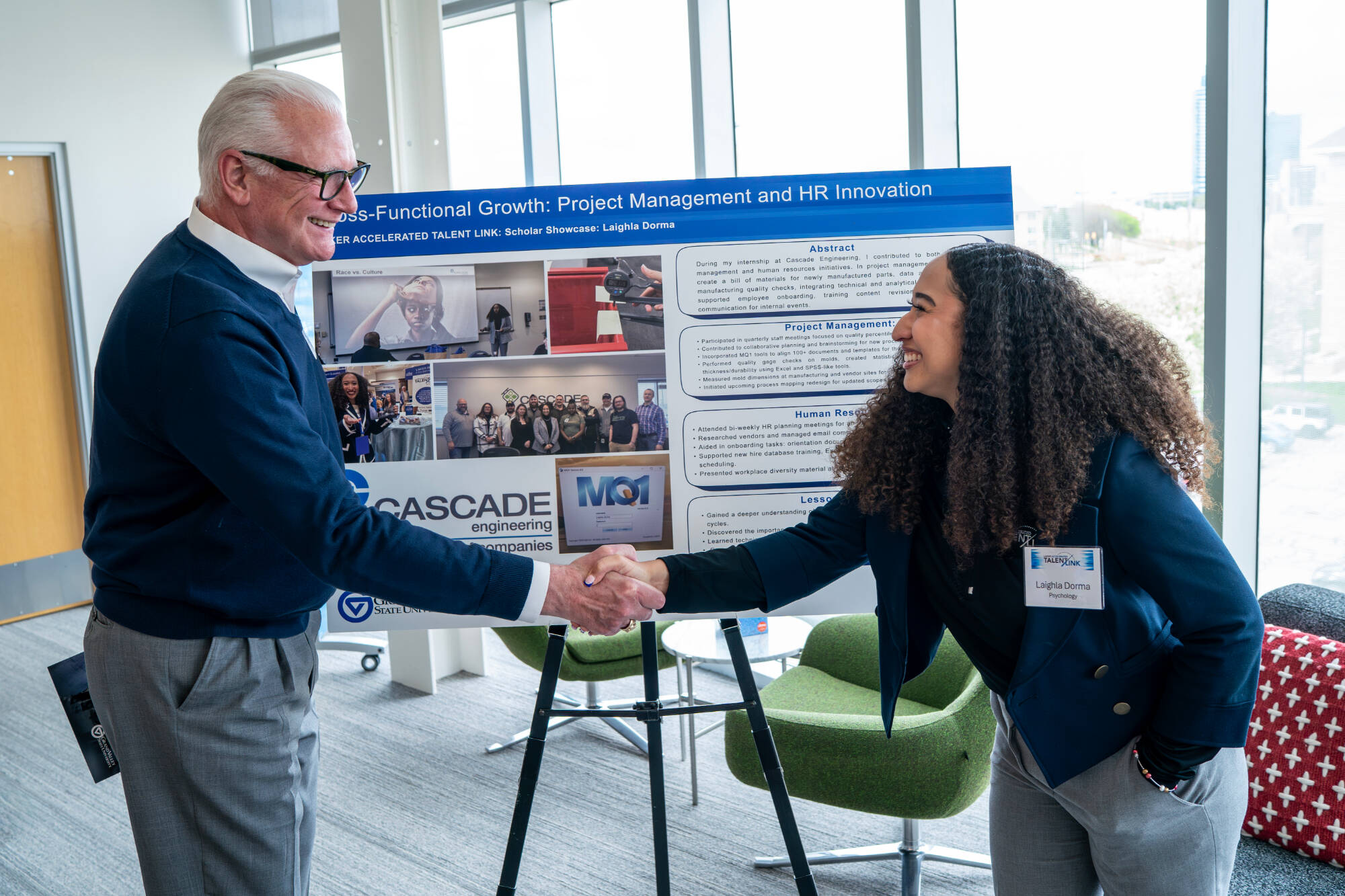 Recent graduate Laighla Dorma, and adjunct faculty with the College of Computing, Michael Worden, shake next to the Cascade Engineering booth